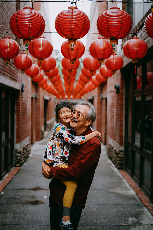 爷爷牵着孙女，面带微笑地走在台湾大街上图片下载