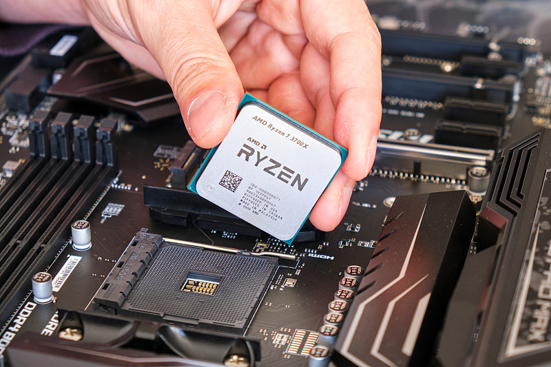 AMD锐龙3700X CPU在技术员的手指上，上面有一块主板，一部分自定义的PC构建。图片下载