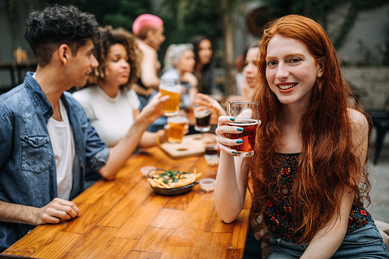 可爱的姜味女人在酒吧和朋友喝啤酒图片下载