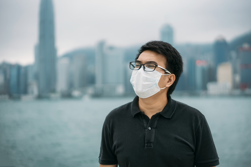 亚洲男子戴着防护口罩在城市由于污染的空气在中国香港图片素材