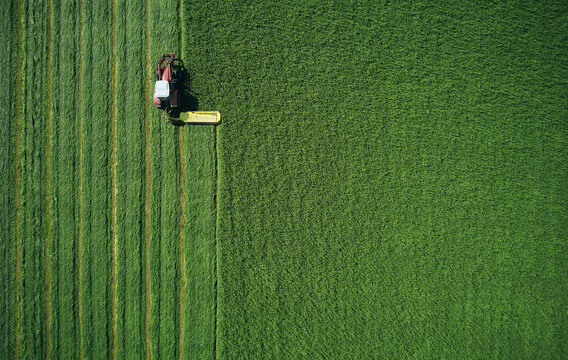 拖拉机在绿色的田野上对称地耕作图片素材