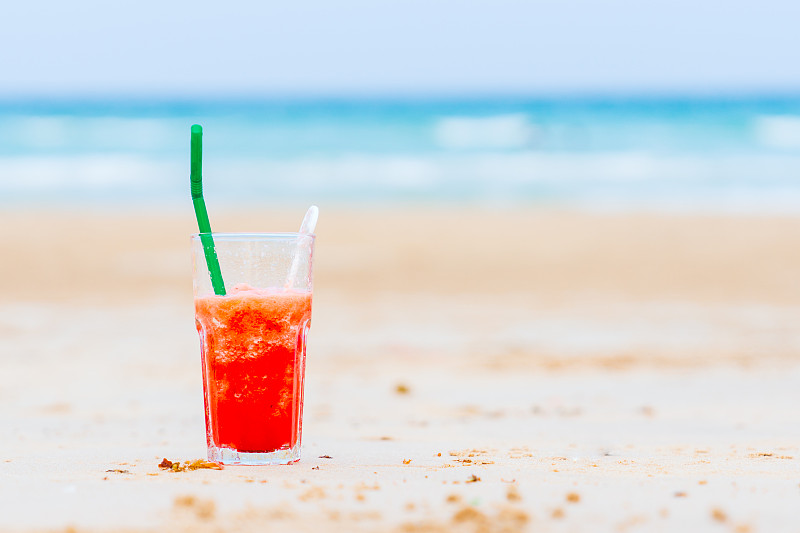 暑假的概念。夏日健康的冰沙在沙滩上畅饮，清新健康。图片素材