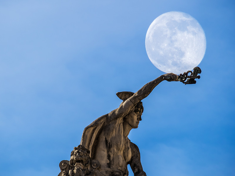 低角度的雕像对蓝天与月亮图片素材