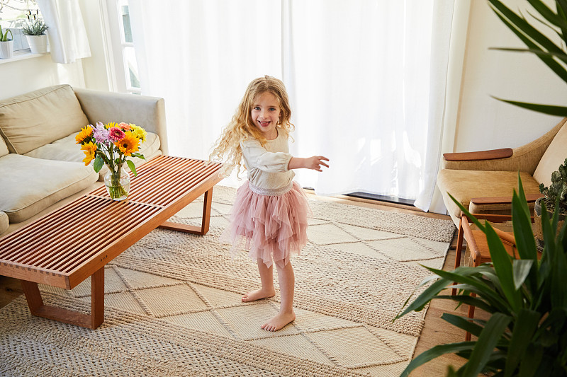 微笑的小女孩穿着芭蕾舞裙在家里跳舞图片下载