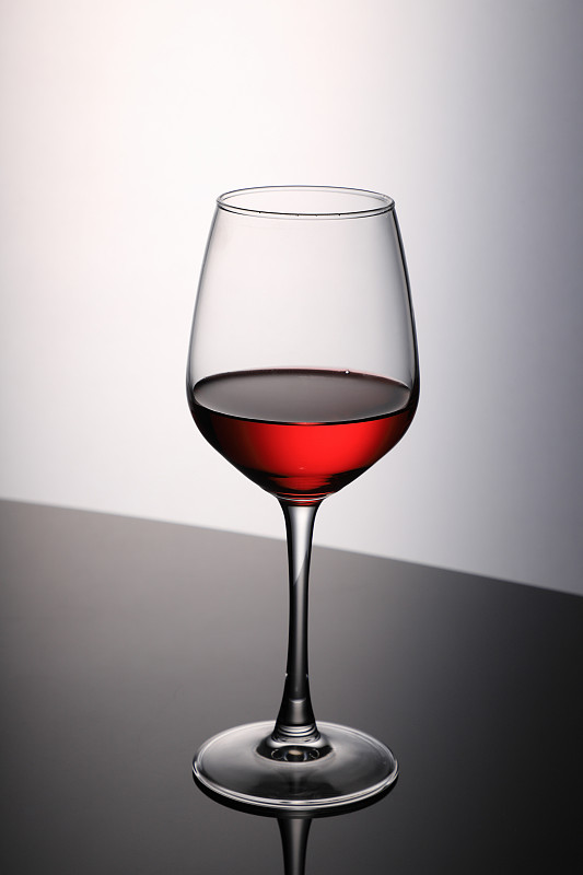 黑桌上白背景上的红酒杯图片素材
