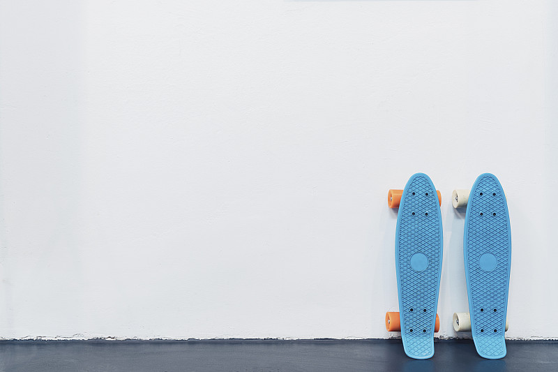 蓝色的滑板靠在白色的墙上图片素材