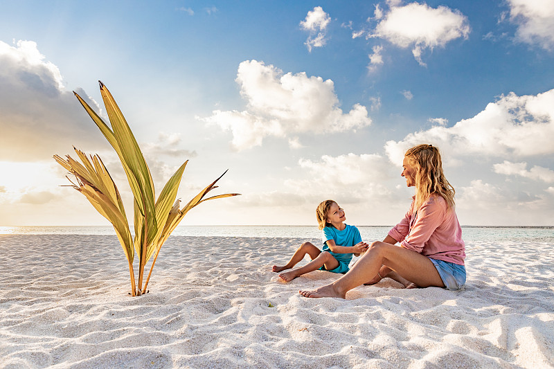 快乐的单身母亲在沙滩上和她的小男孩说话。图片下载