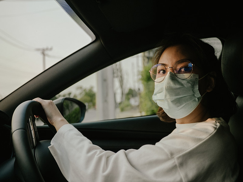 坐在车里的女人戴着保护面膜。健康保护。图片素材