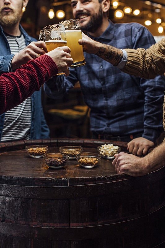 一群男人在酒吧与啤酒干杯，一个近距离图片下载