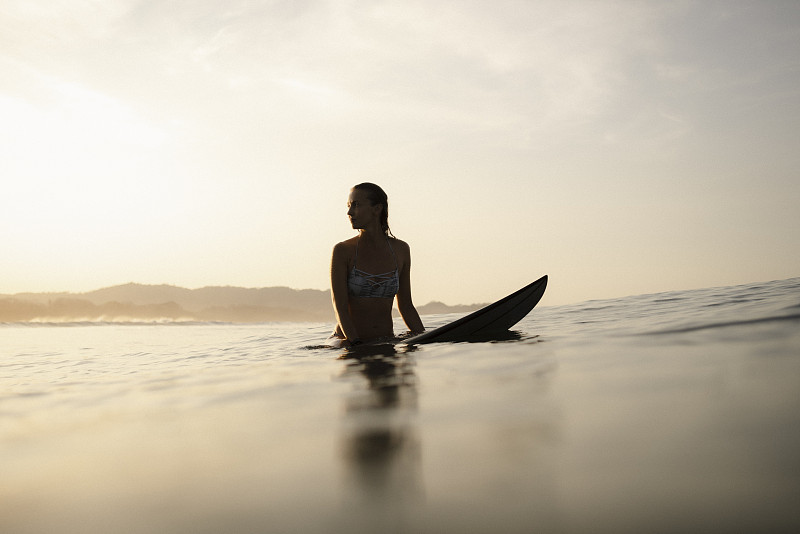 女冲浪者晚上坐在冲浪板上，哥斯达黎加图片下载