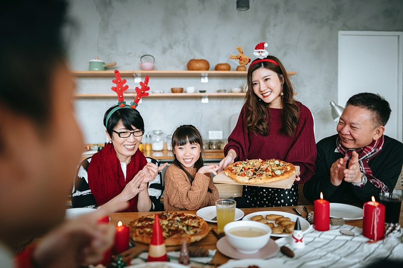 快乐的亚洲多代家庭花时间在一起庆祝圣诞节，微笑的年轻女子在圣诞节期间在家里为家人提供食物图片下载