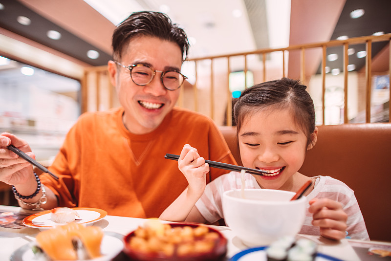 年轻的爸爸和女儿在日式餐厅愉快地享用晚餐图片素材