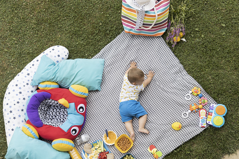 婴儿躺在绿草地上的毯子上。从上面的照片。上面的观点。摄影图片