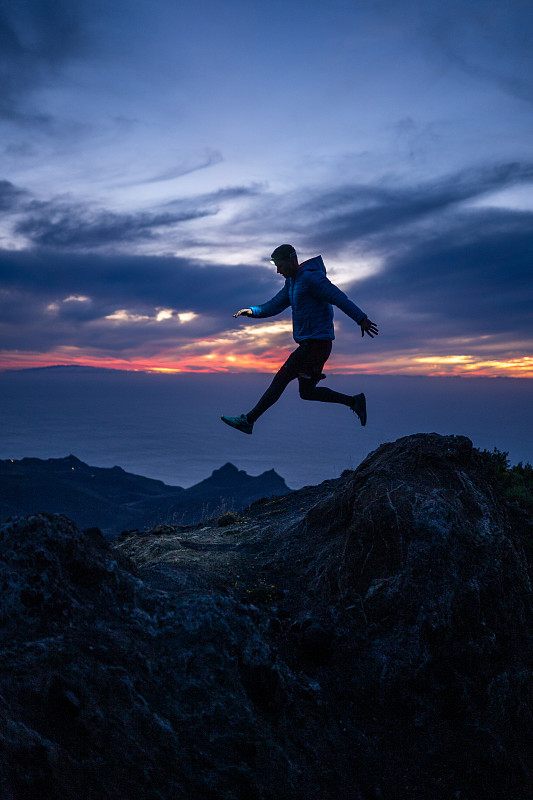 西班牙加那利群岛，戈梅拉岛，一名男子正从岩脊上跳下来图片素材