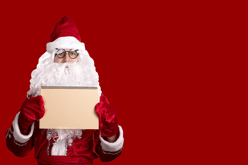 圣诞节。善良的圣诞老人拿着一个空的纸板框架。放置广告、文字、空白处图片下载