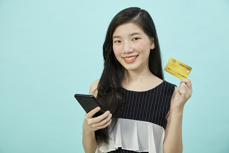 美丽的亚洲女性使用智能手机和信用卡在网上购物图片下载