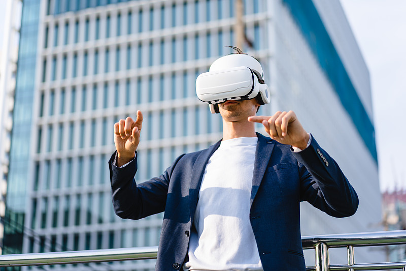 商人戴着VR护目镜看现代城市中的虚拟建筑图片下载