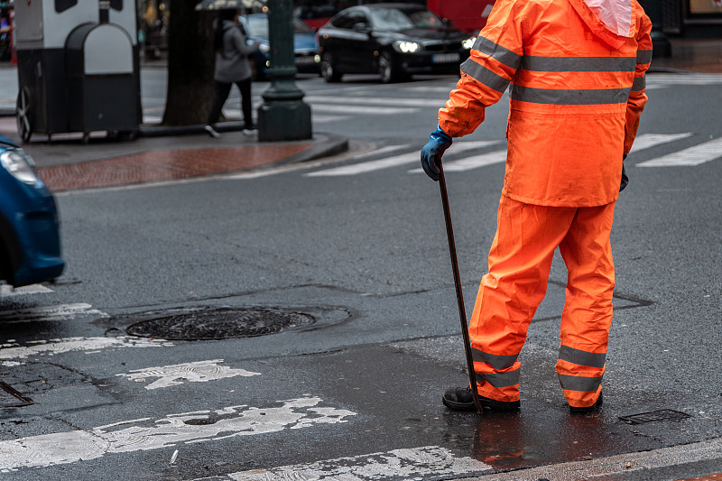 下雨天穿着橙色雨衣，手里拿着工具的工人图片下载