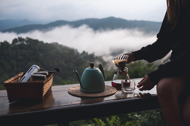 特写图像的一个女人做滴滤咖啡与美丽的山和自然景观的背景图片下载