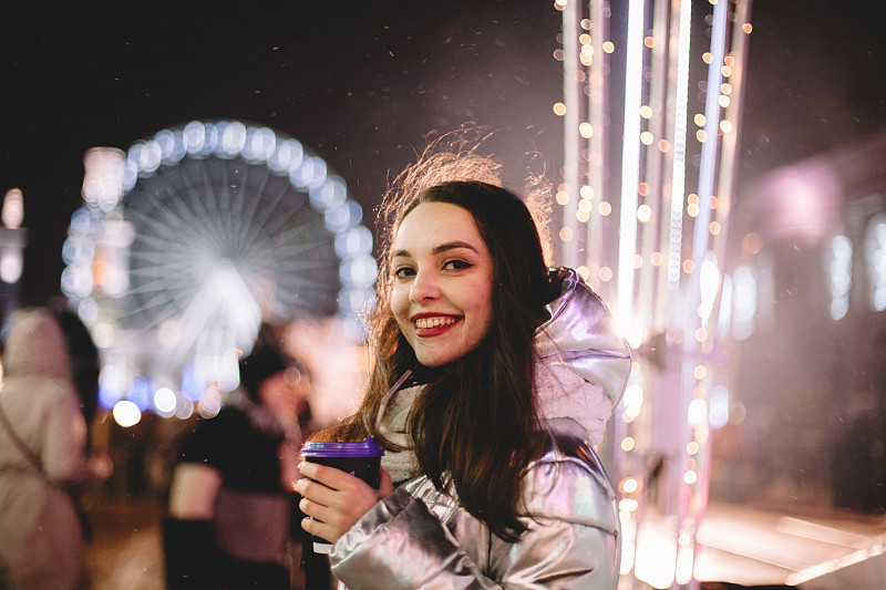 幸福的年轻女子站在圣诞市场的画像在城市的夜晚图片下载