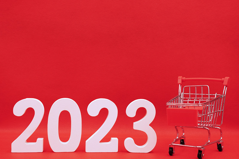 2023数字与红色礼盒在购物车上的红色图案背景- 2022年年底和2023年新年快乐的概念-网上购物盒，营销推广广告设计-假期图片下载