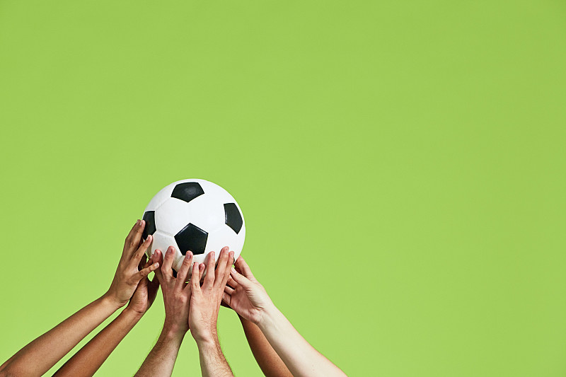 足球时间!许多不同的球迷或选手的手伸向高举着的足球图片下载