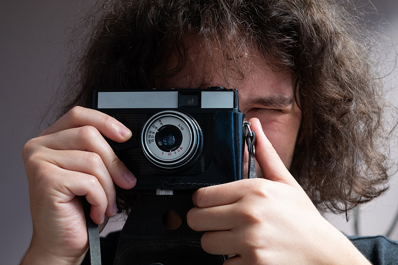 一个男人用复古相机拍照,拿在手里