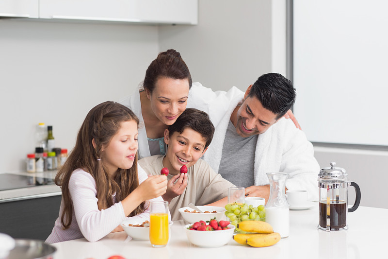 快乐的孩子和父母在厨房享受早餐图片素材