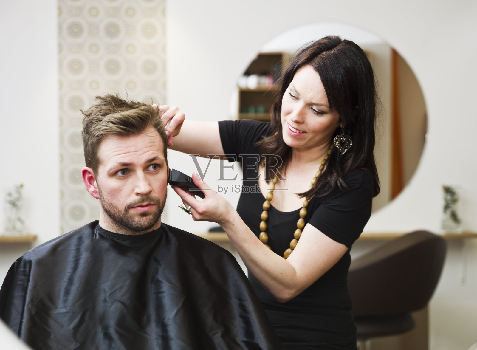 一个黑发女人在理发店给一个男人剪头发照片摄影图片