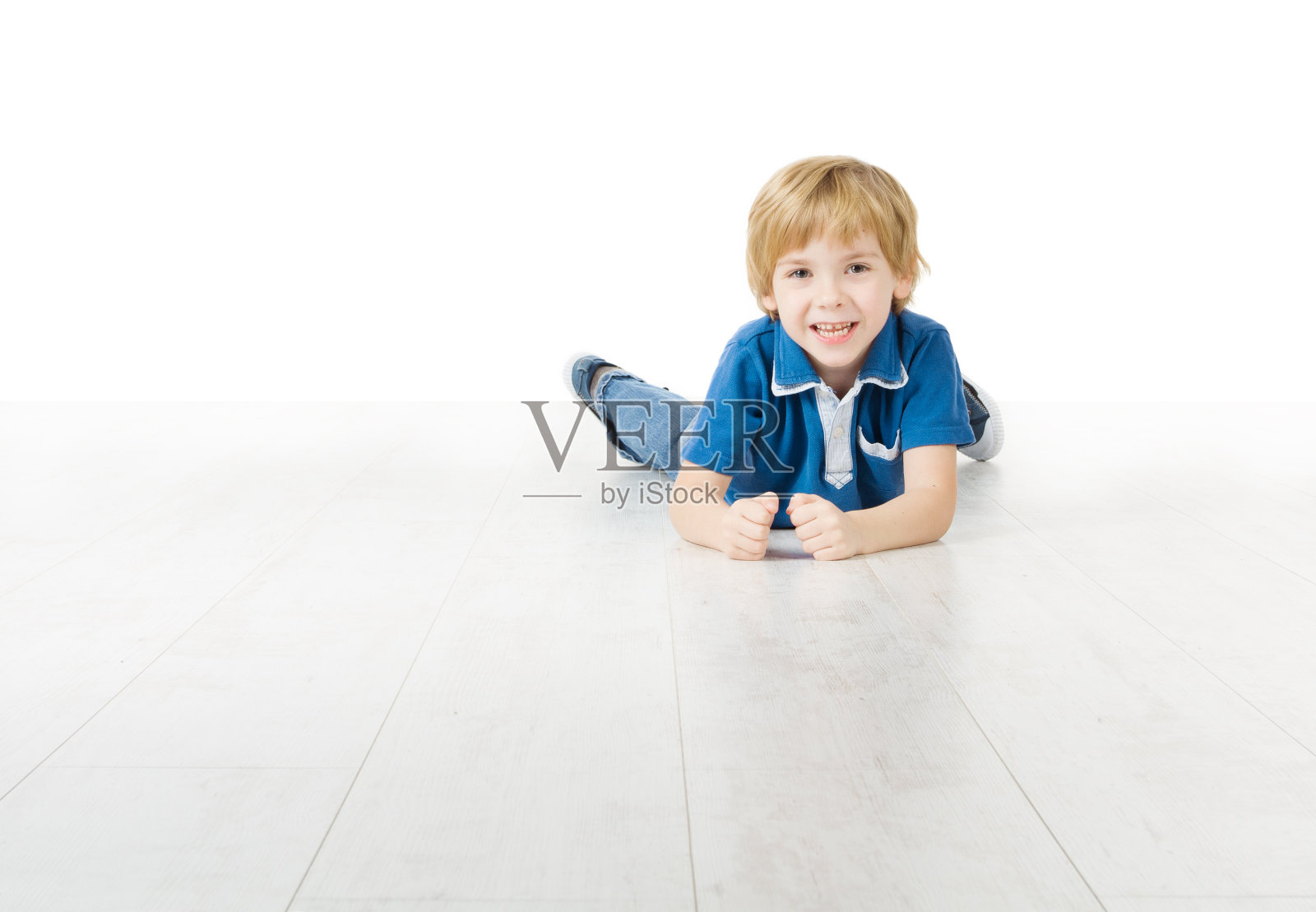 微笑的男孩躺在白色的地板上照片摄影图片
