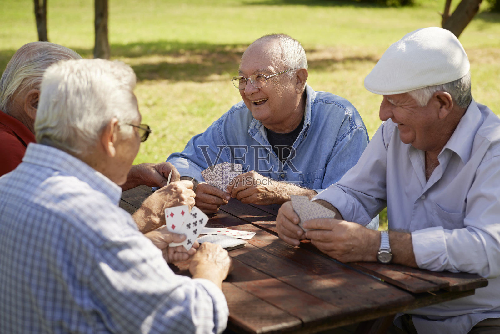 一群老人，微笑着在公园里打牌照片摄影图片