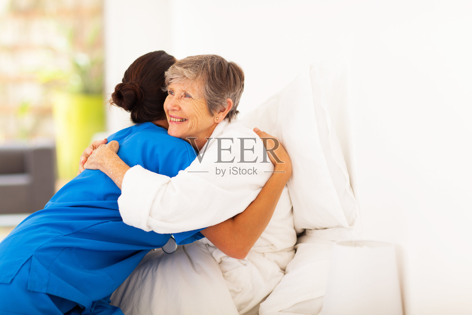 老年妇女在床上拥抱照顾者照片摄影图片