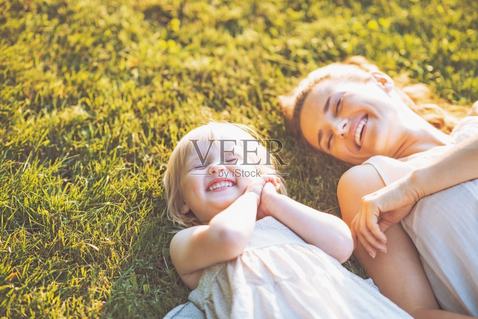 微笑的母亲和婴儿躺在草地上照片摄影图片