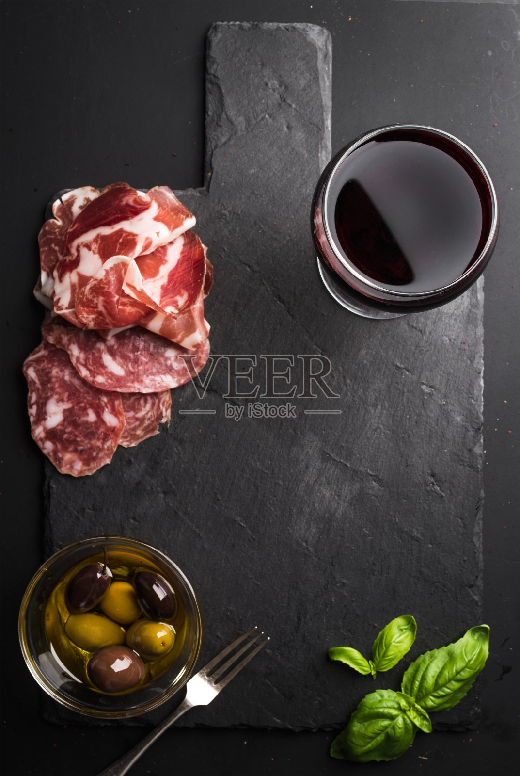 一杯红酒，肉开胃菜，橄榄和罗勒照片摄影图片
