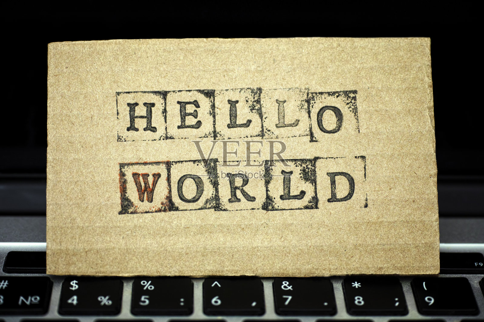 在笔记本电脑键盘上写着Hello World的硬纸板照片摄影图片