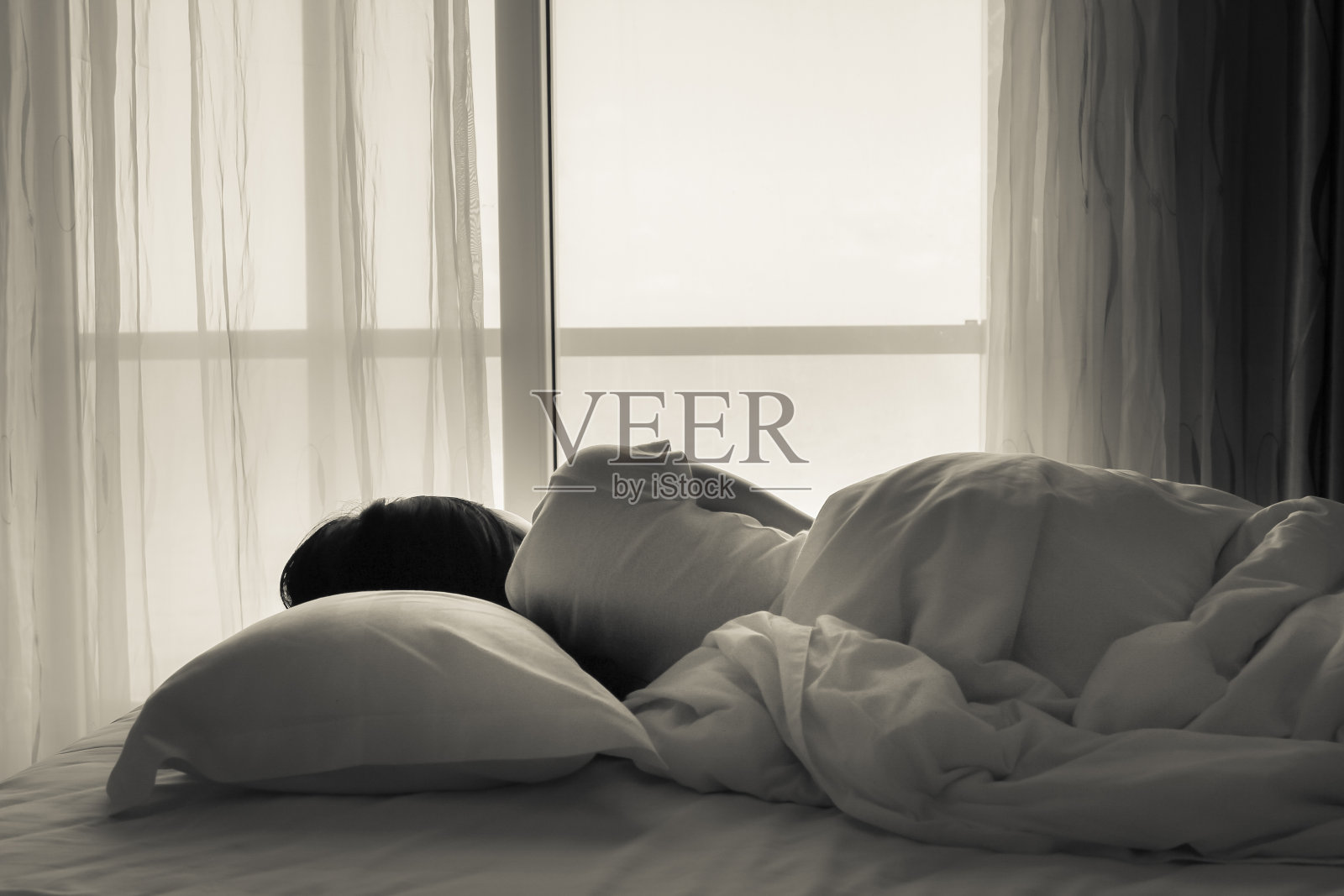 一个年轻女子睡在窗边的床上照片摄影图片
