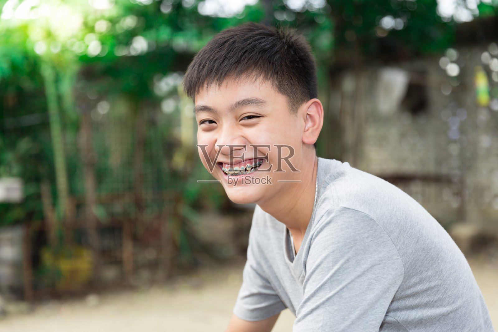 美丽的微笑英俊的男孩用牙齿支撑牙齿。照片摄影图片