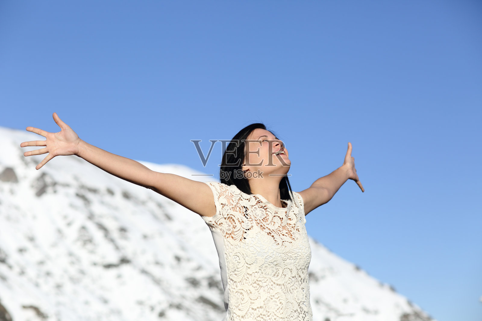 快乐的女人在冬天深呼吸，举起双臂照片摄影图片