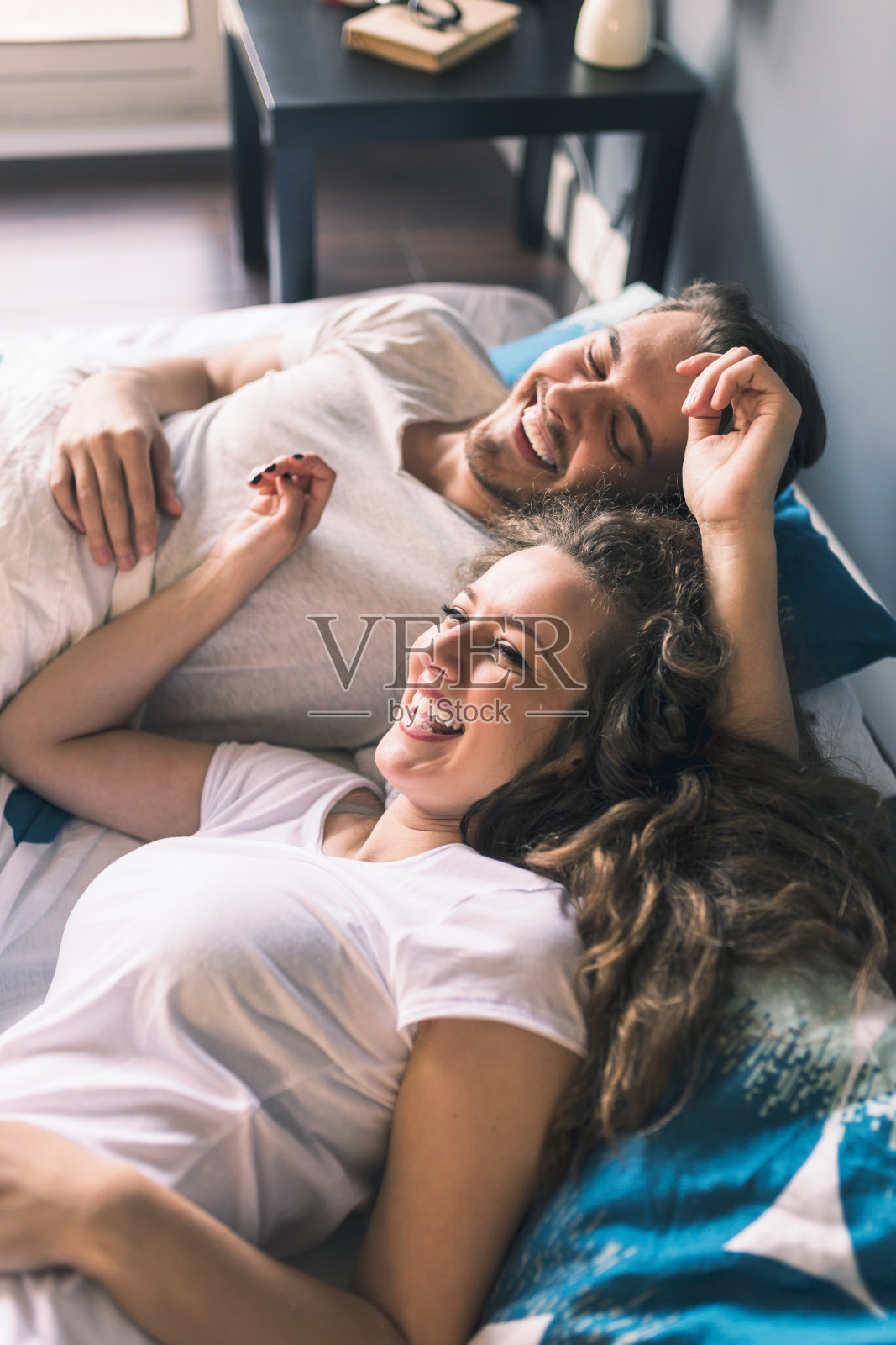 年轻夫妇躺在床上微笑着照片摄影图片