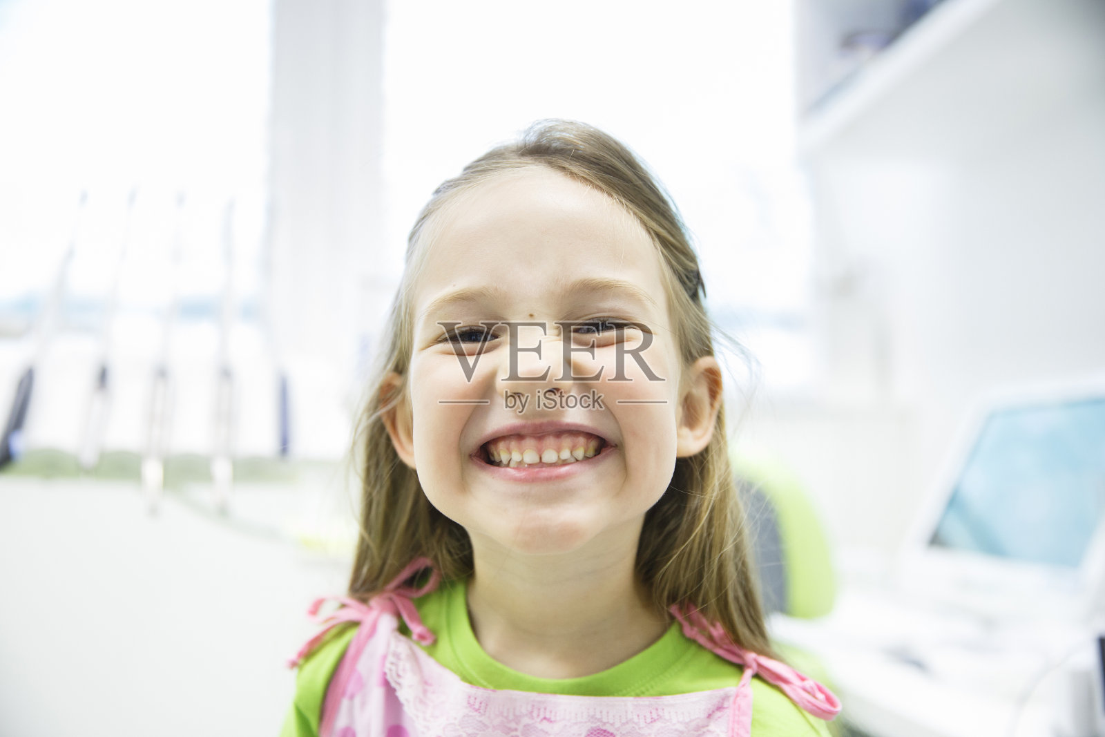 女孩在牙科诊所展示她健康的乳牙照片摄影图片