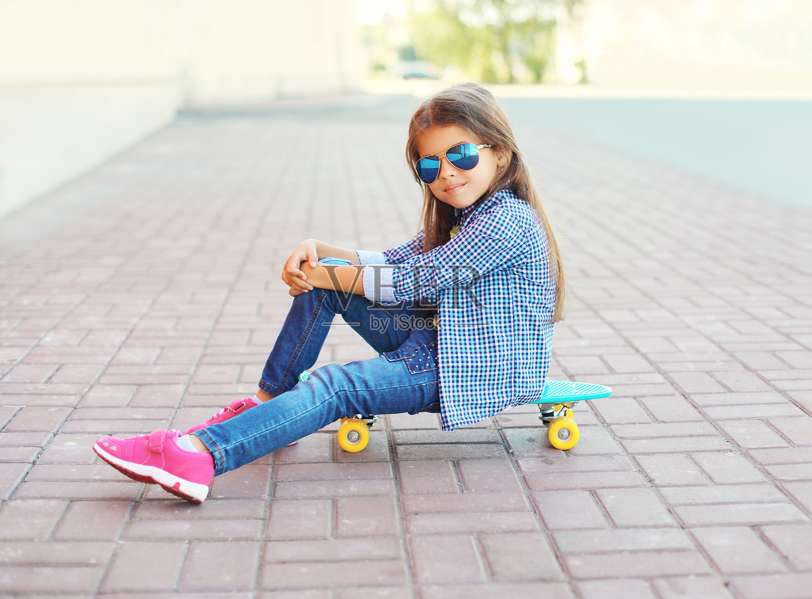 美丽的小女孩坐在滑板上在城市照片摄影图片