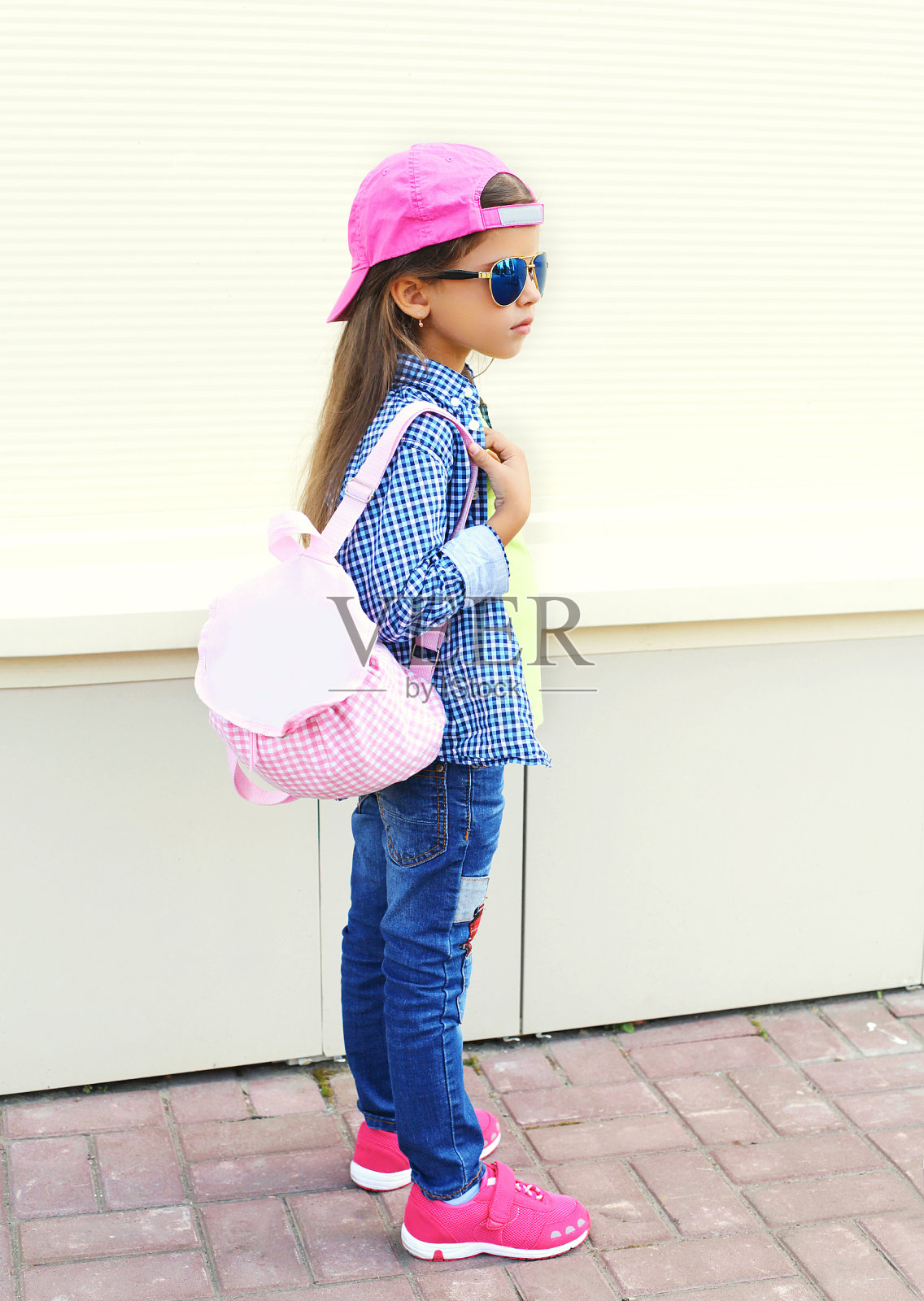 时尚小女孩戴着太阳镜，粉色棒球帽照片摄影图片
