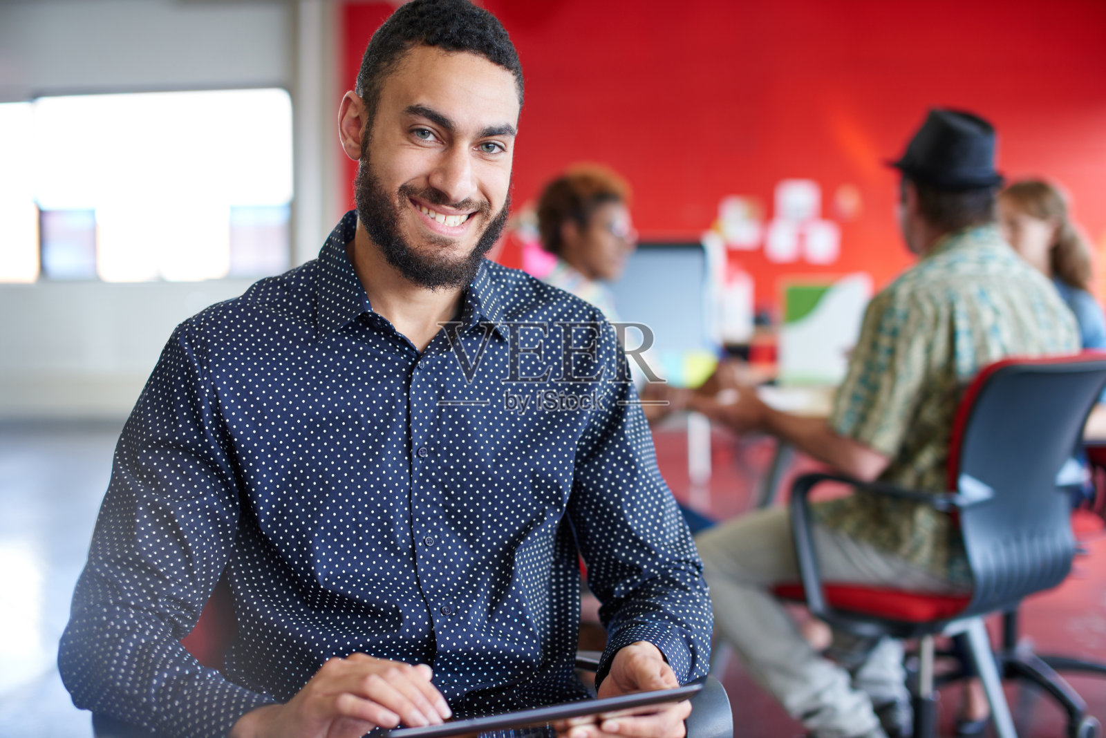 自信的男性设计师正在用红色的平板电脑工作照片摄影图片