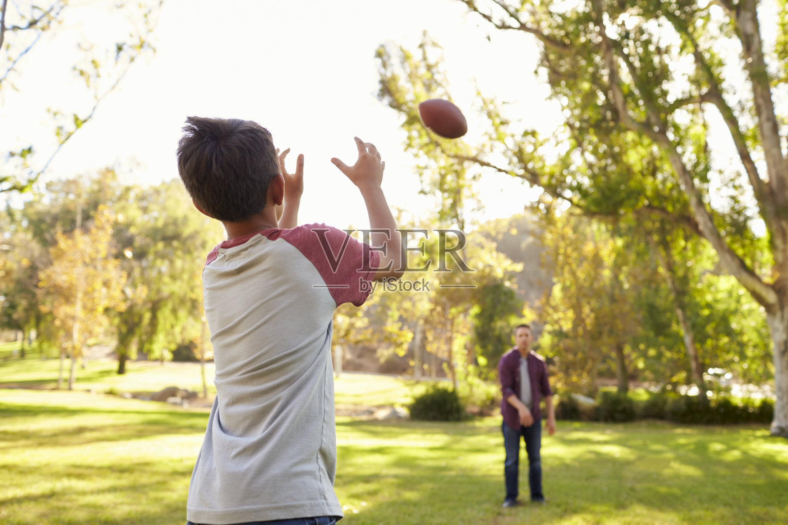 爸爸和儿子互相扔美式足球照片摄影图片
