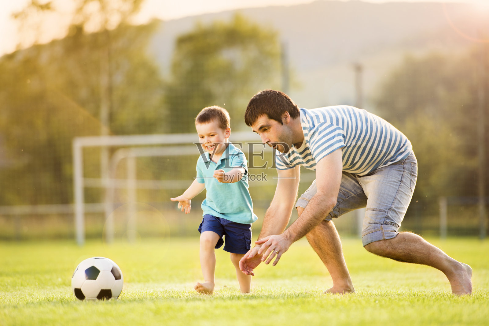 父亲和儿子在踢足球照片摄影图片