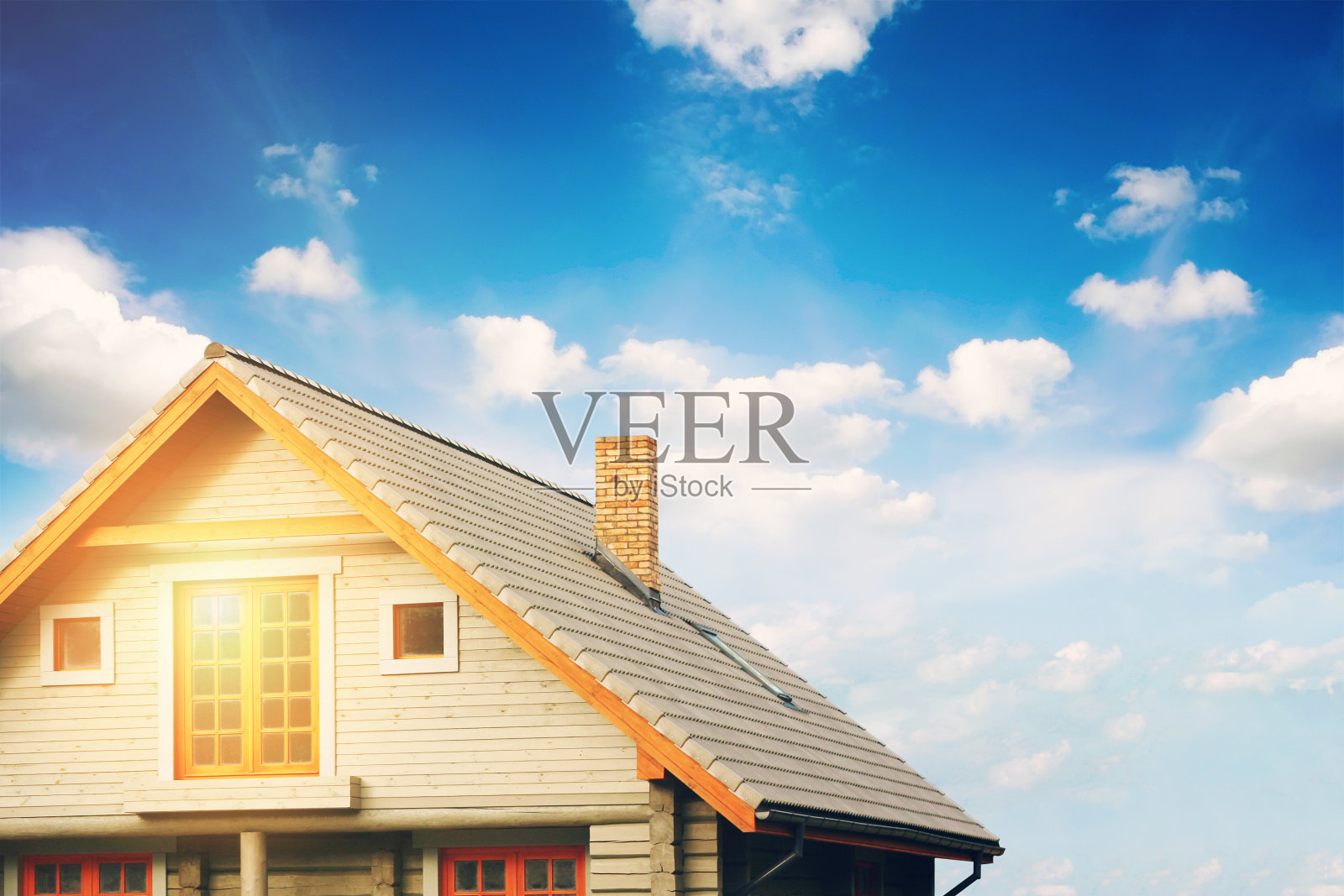 蓝色天空衬托着灰色瓦屋顶的原木小屋照片摄影图片