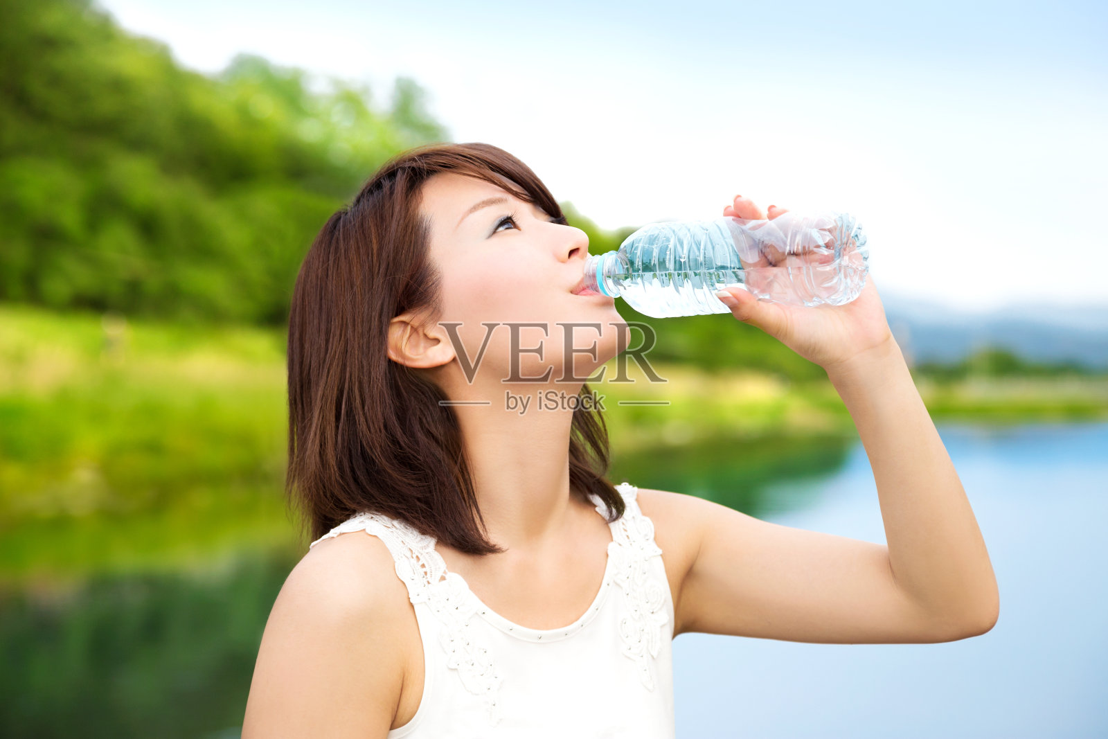 美丽的亚洲女孩在大自然中喝着这瓶水照片摄影图片