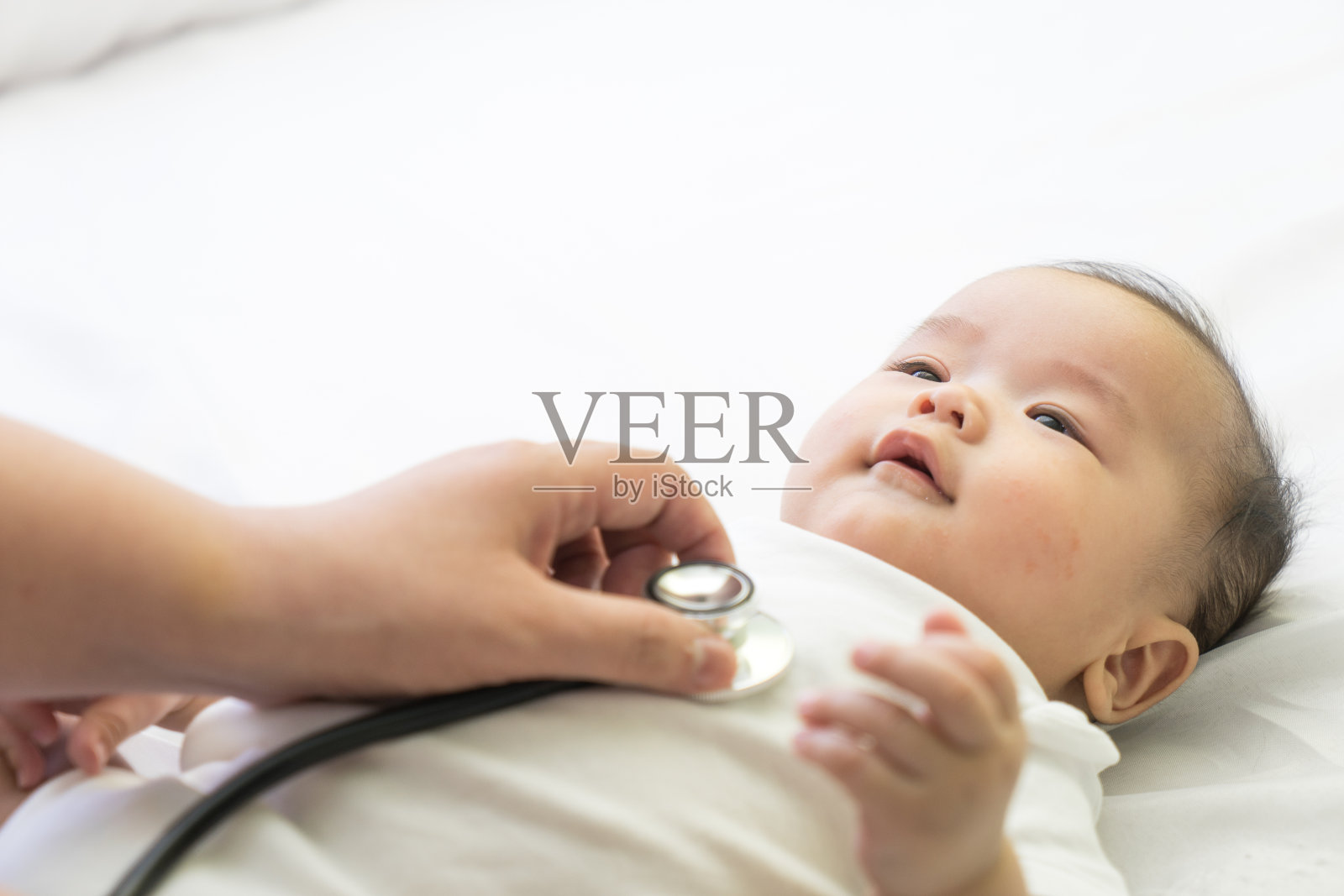 在医院里，医生用听诊器给新生的亚洲婴儿做检查照片摄影图片