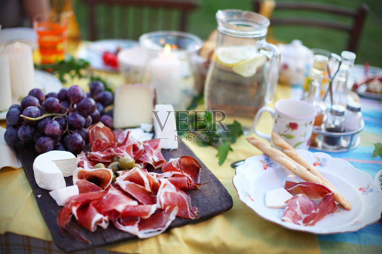 野餐桌上放着意大利熏火腿、奶酪和葡萄照片摄影图片