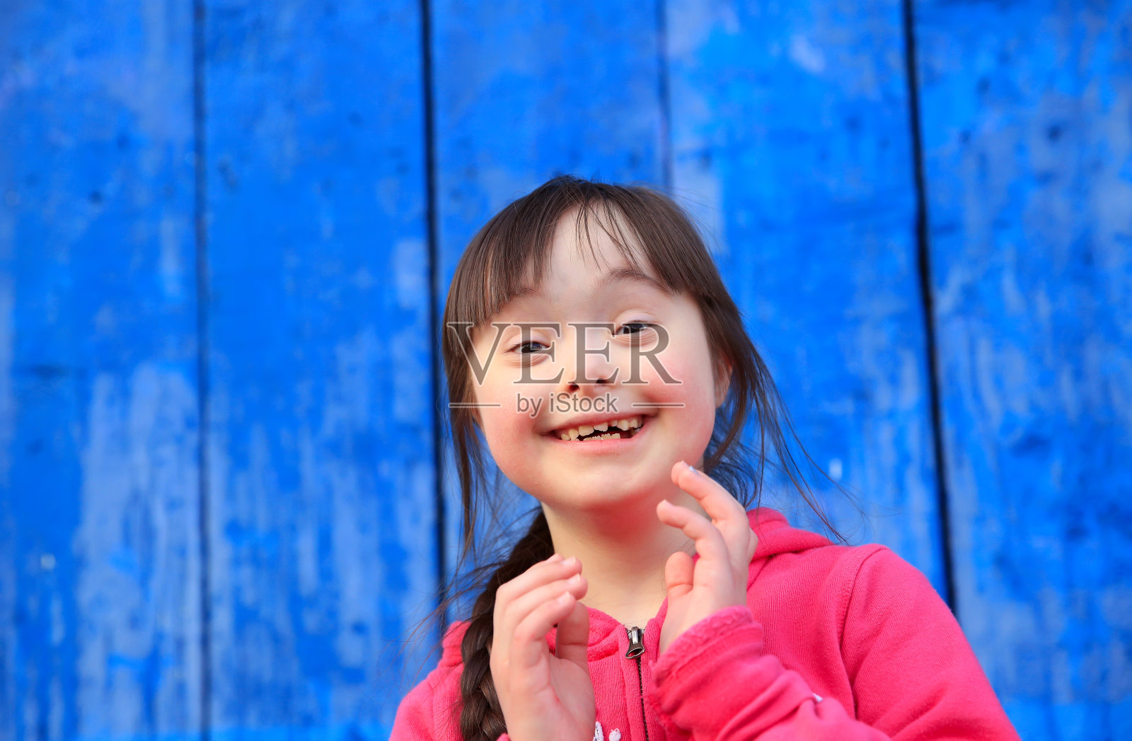 年轻的女孩在蓝色的墙壁上微笑照片摄影图片